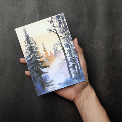 Flat cardstock note card featuring original watercolor piece Winter Wood in a person's right hand. The background transitions from black at the bottom to a dull gray at the top.