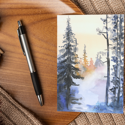 Flat cardstock note card featuring original watercolor piece Winter Wood displayed on a wooden surface beside a black and silver pen.