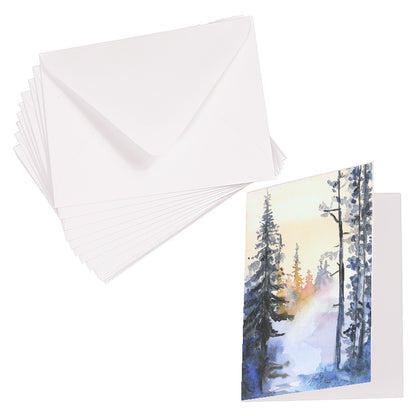 Folding cardstock greeting card featuring original watercolor piece Winter Wood laying next to a stack of euro flap envelopes.